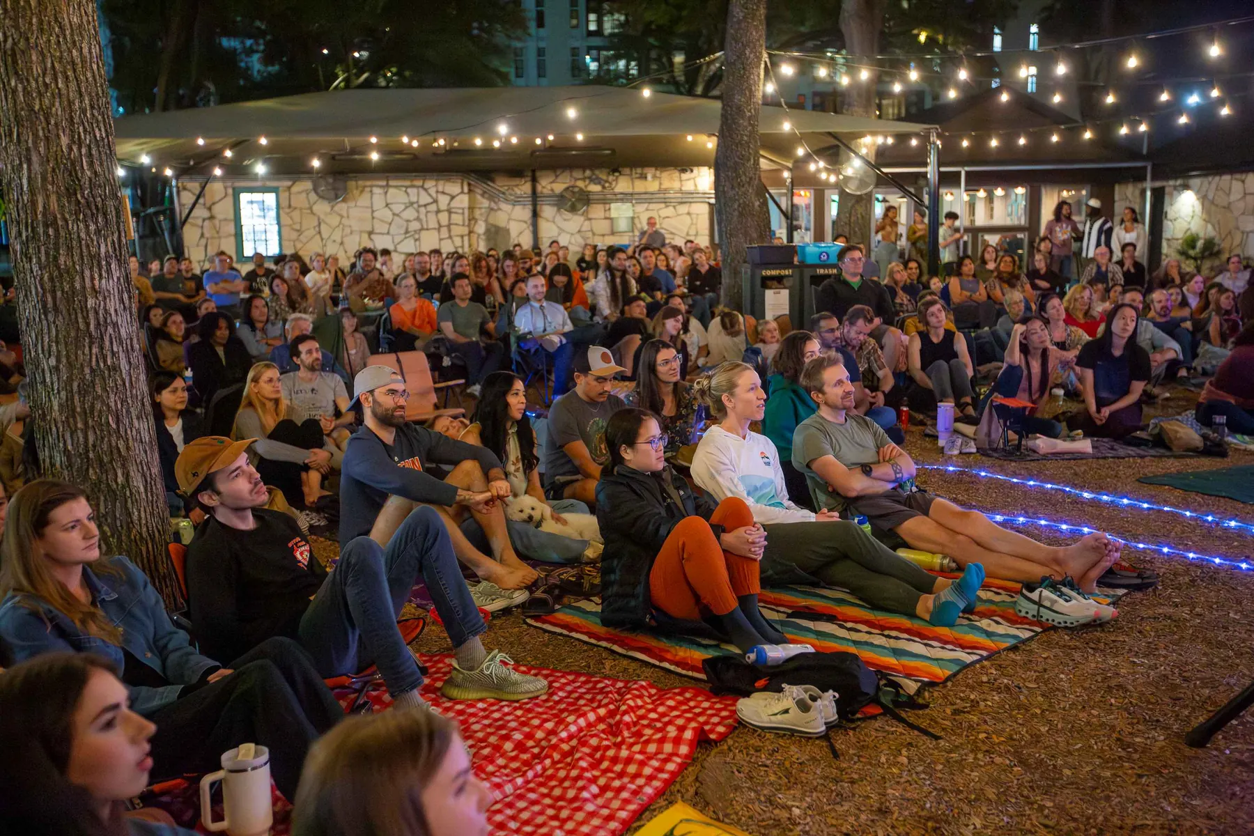 Audience gathered under string lights at Hyde Park Storytelling